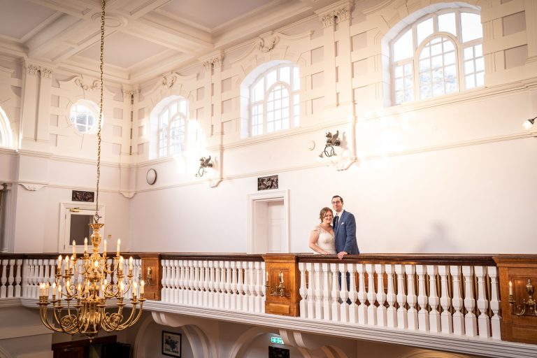 Bride and groom in elegant venue with chandelier by Southampton wedding photographer John Watson