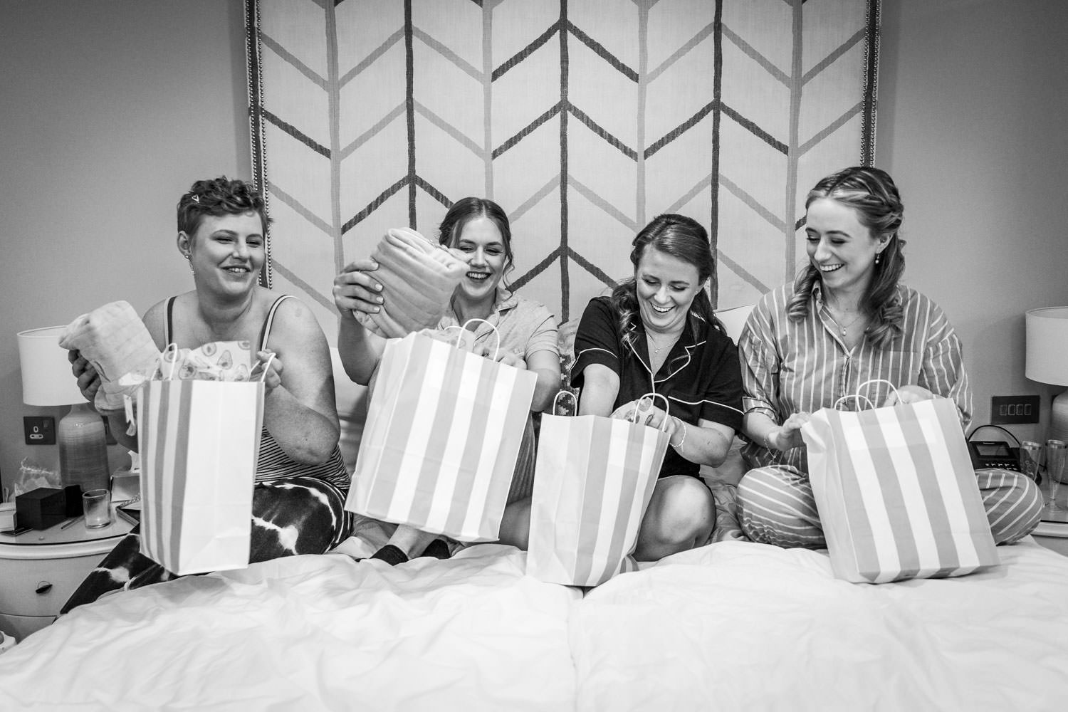 Wedding party opening gift bags on bed by Southampton wedding photographer John Watson