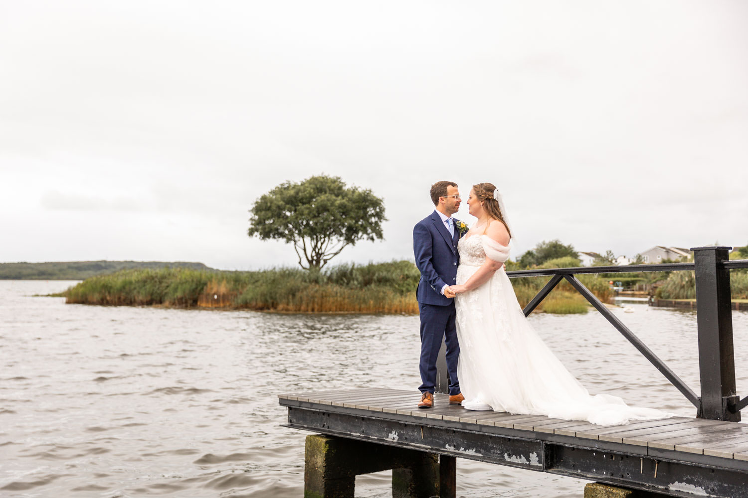 Bride and groom on pier by lake by Southampton wedding photographer John Watson