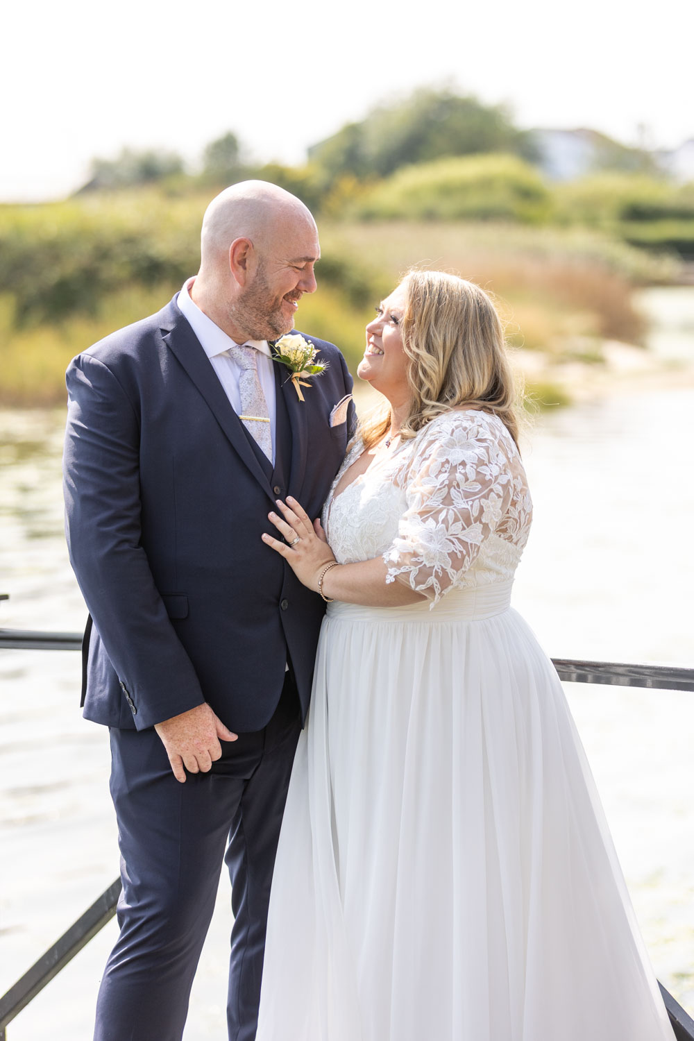 Bride and groom smiling by waterfront by Southampton wedding photographer John Watson