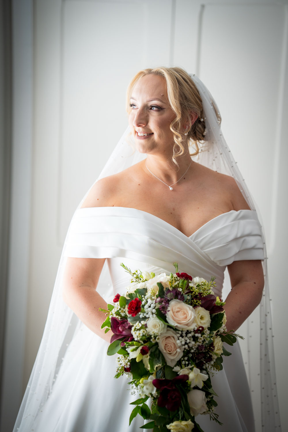 Bride smiling in elegant gown holding bouquet by Southampton wedding photographer John Watson