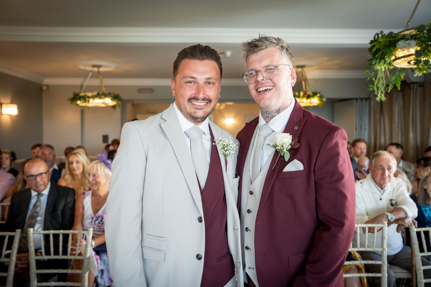 Two grooms beaming at their wedding ceremony by Southampton wedding photographer John Watson