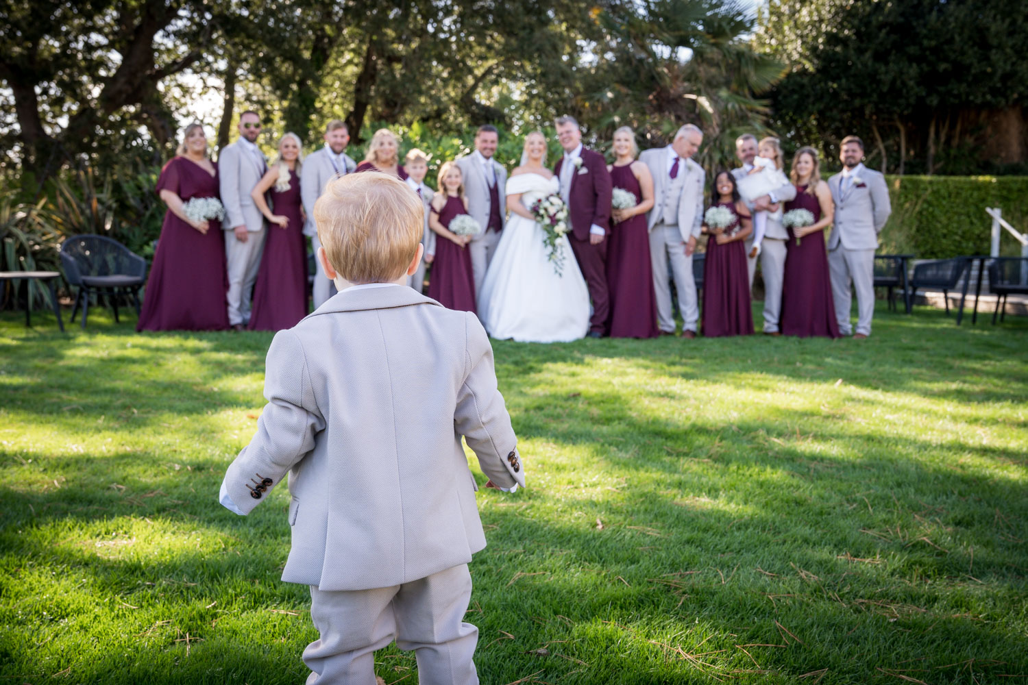 Toddler approaches wedding group on grass by Southampton wedding photographer John Watson
