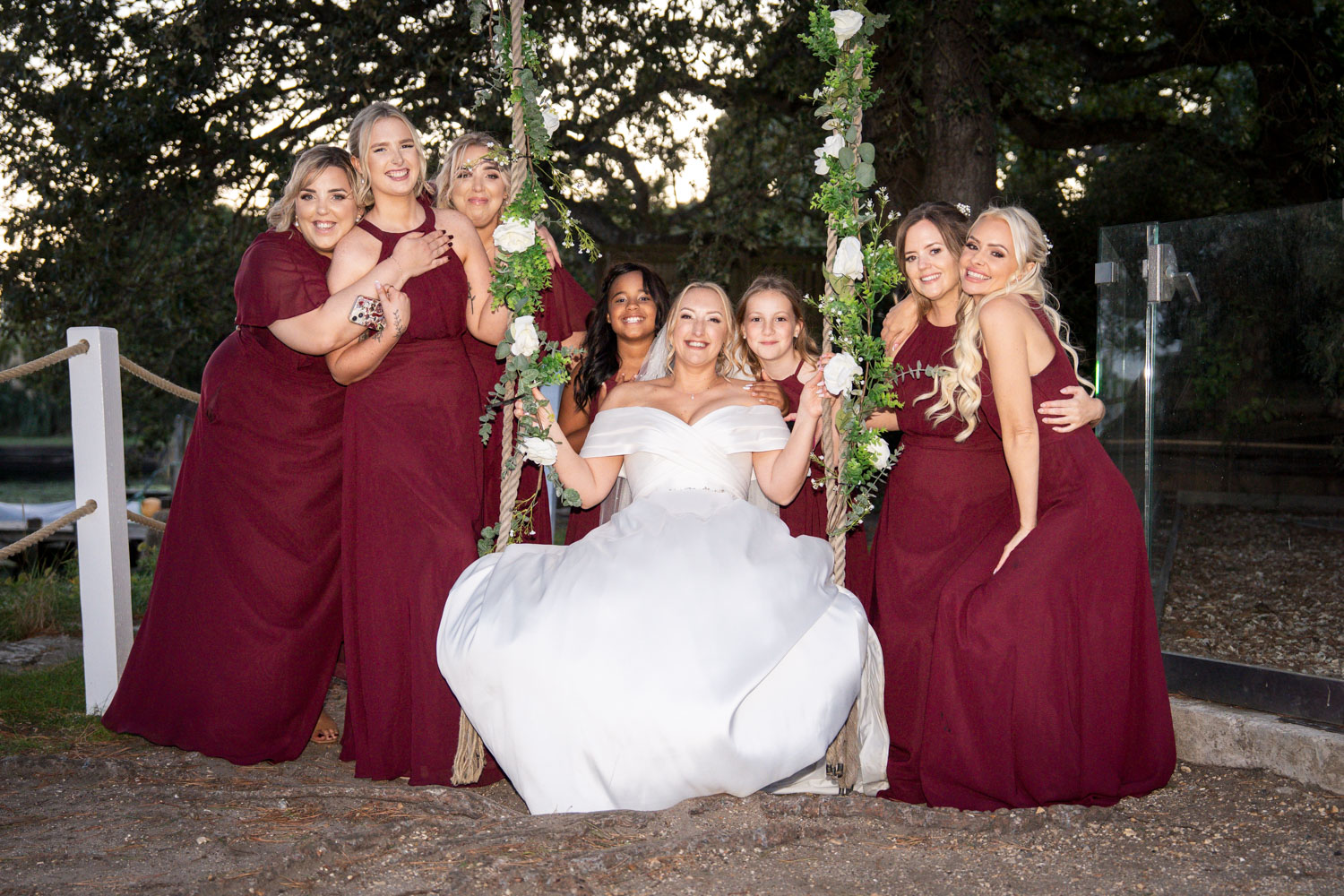 Bride with bridesmaids in maroon dresses smiling by Southampton wedding photographer John Watson