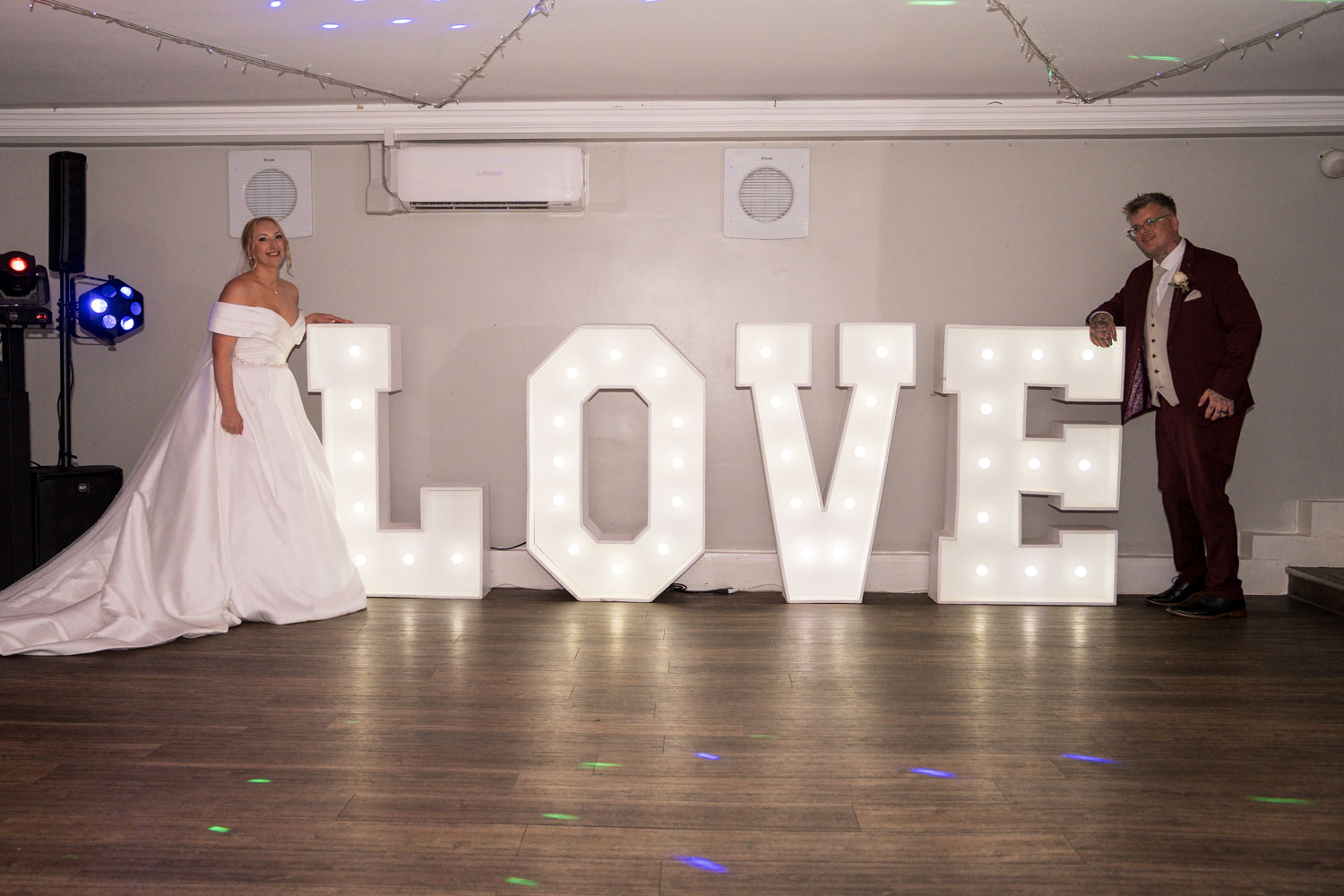 Bride and groom with illuminated LOVE sign by Southampton wedding photographer John Watson
