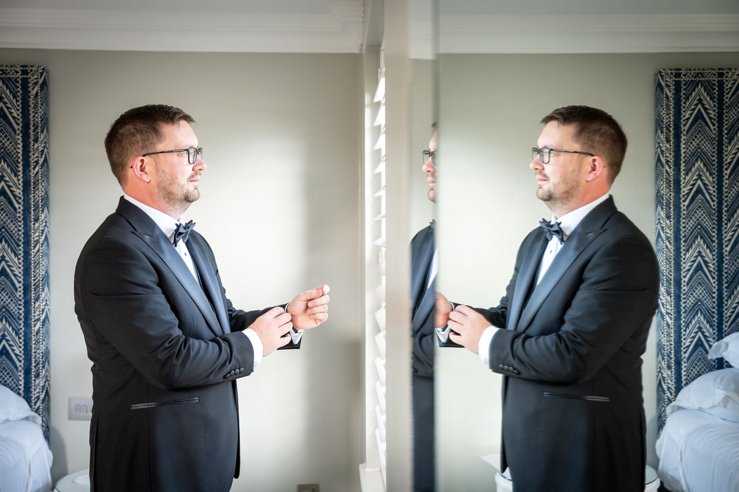 Groom adjusting cuffs in mirror reflection by Southampton wedding photographer John Watson