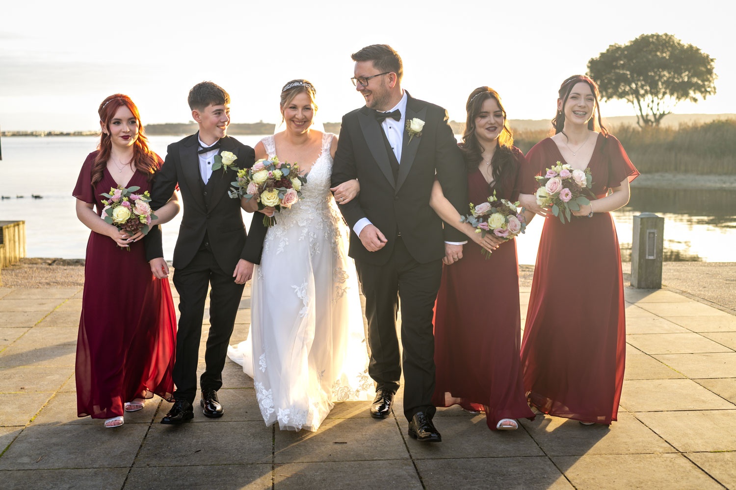 A joyful bridal party stroll near the lake by Southampton wedding photographer John Watson