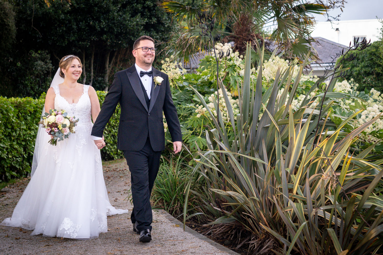 Bride and groom walking in garden setting by Southampton wedding photographer John Watson