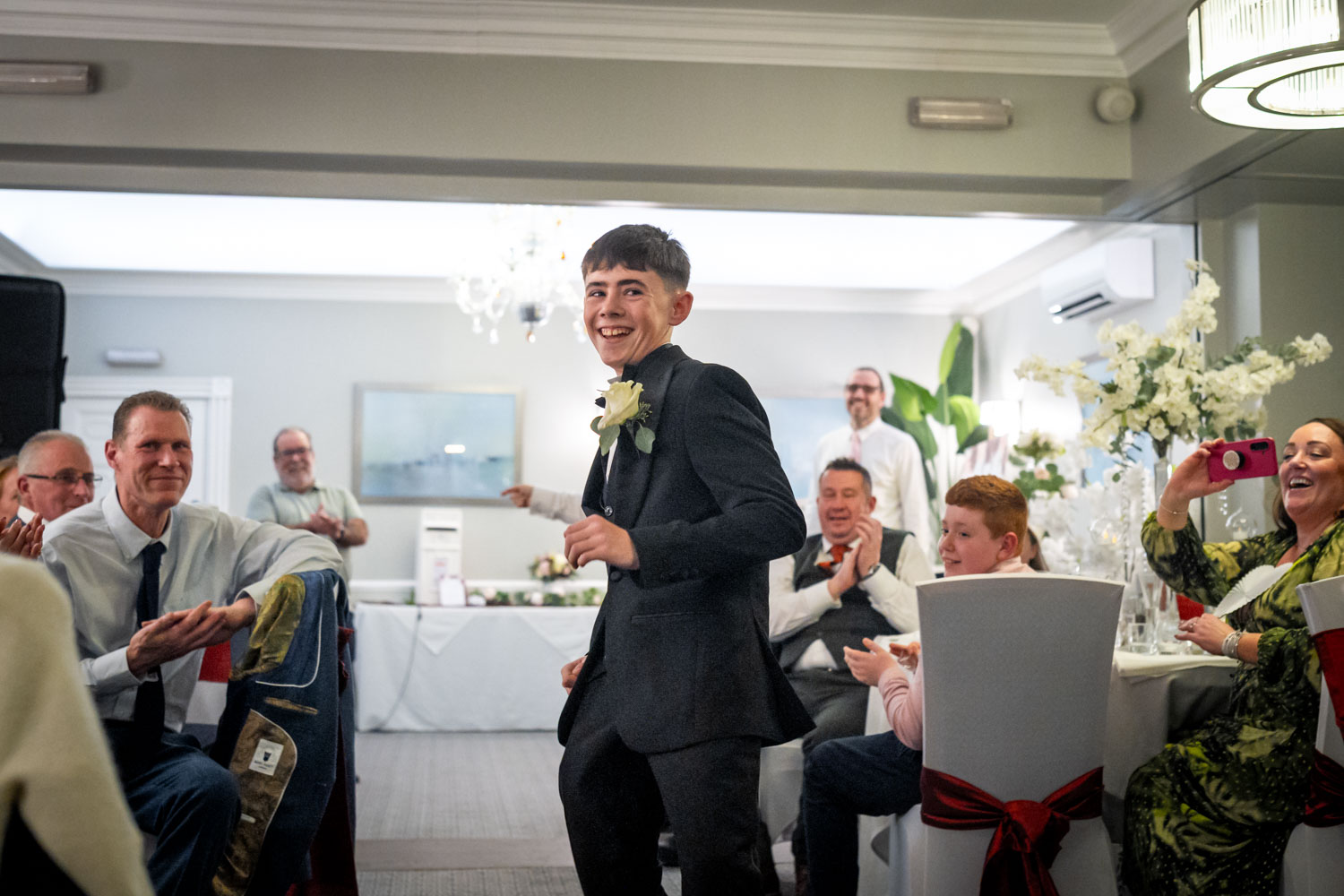Young guest dancing joyfully at wedding reception by Southampton wedding photographer John Watson