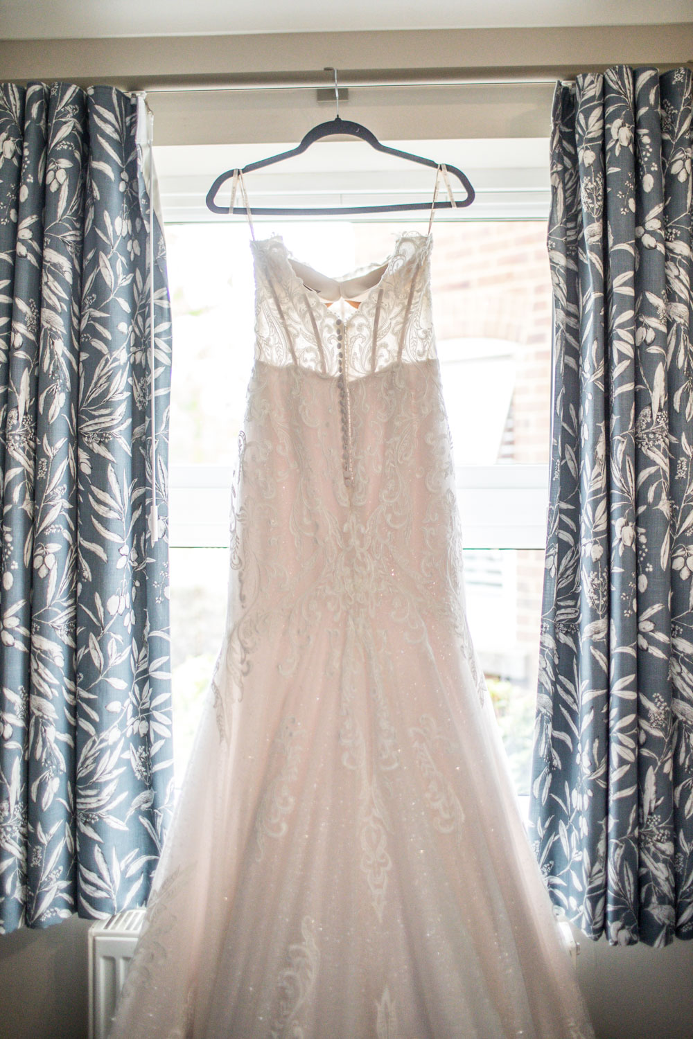 Elegant white wedding dress hanging in sunlight by Southampton wedding photographer John Watson
