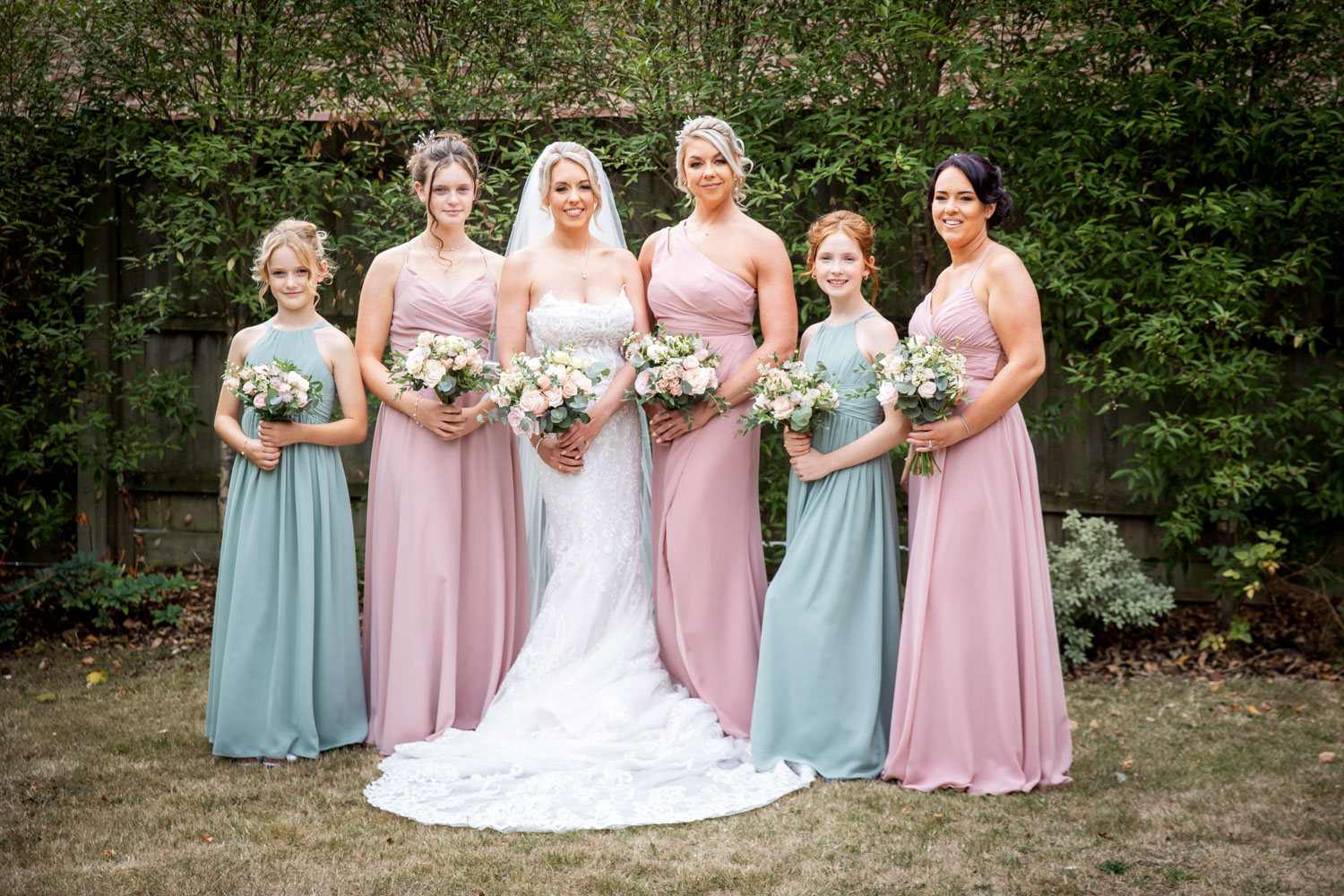 Bridal party with bouquets in garden setting by Southampton wedding photographer John Watson