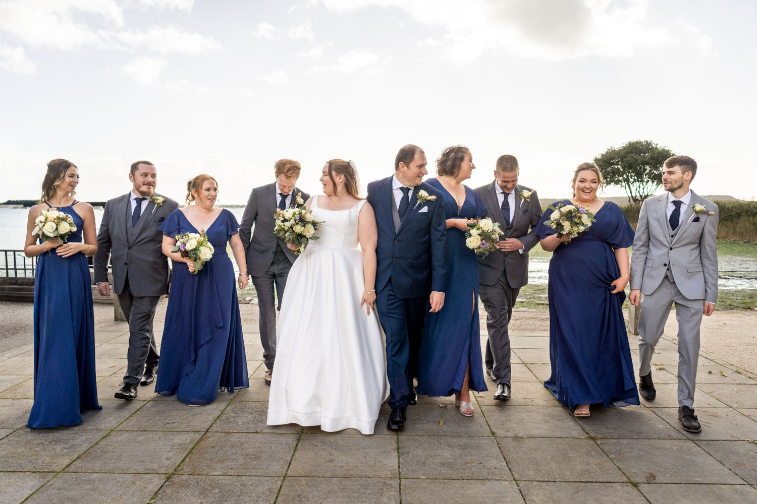 Wedding party walking by water captured by Southampton wedding photographer John Watson