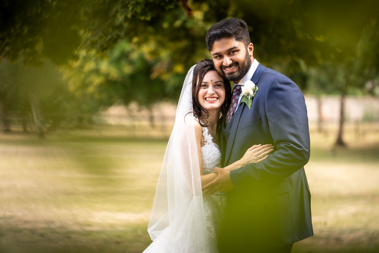 Bride and groom embracing in a sunny garden setting by Southampton wedding photographer John Watson