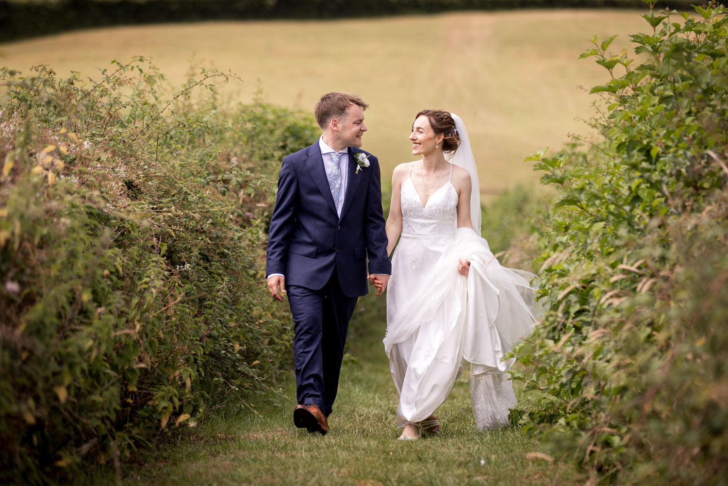 Bride and groom walking in a lush garden by Southampton wedding photographer John Watson