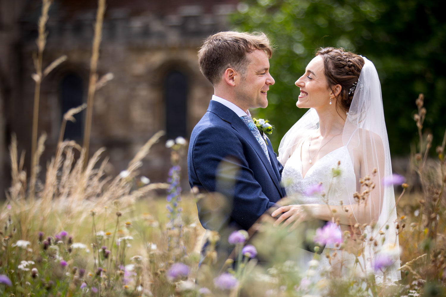 Bride and groom smiling in wildflower meadow by Southampton wedding photographer John Watson
