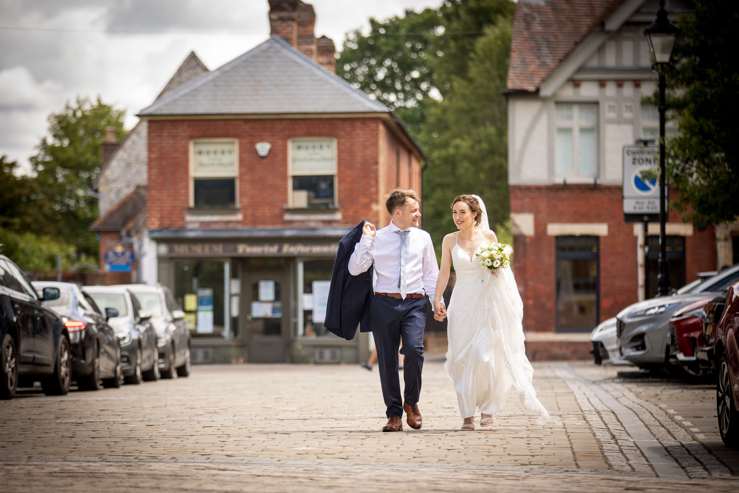 Newlyweds walking down a charming street by Southampton wedding photographer John Watson