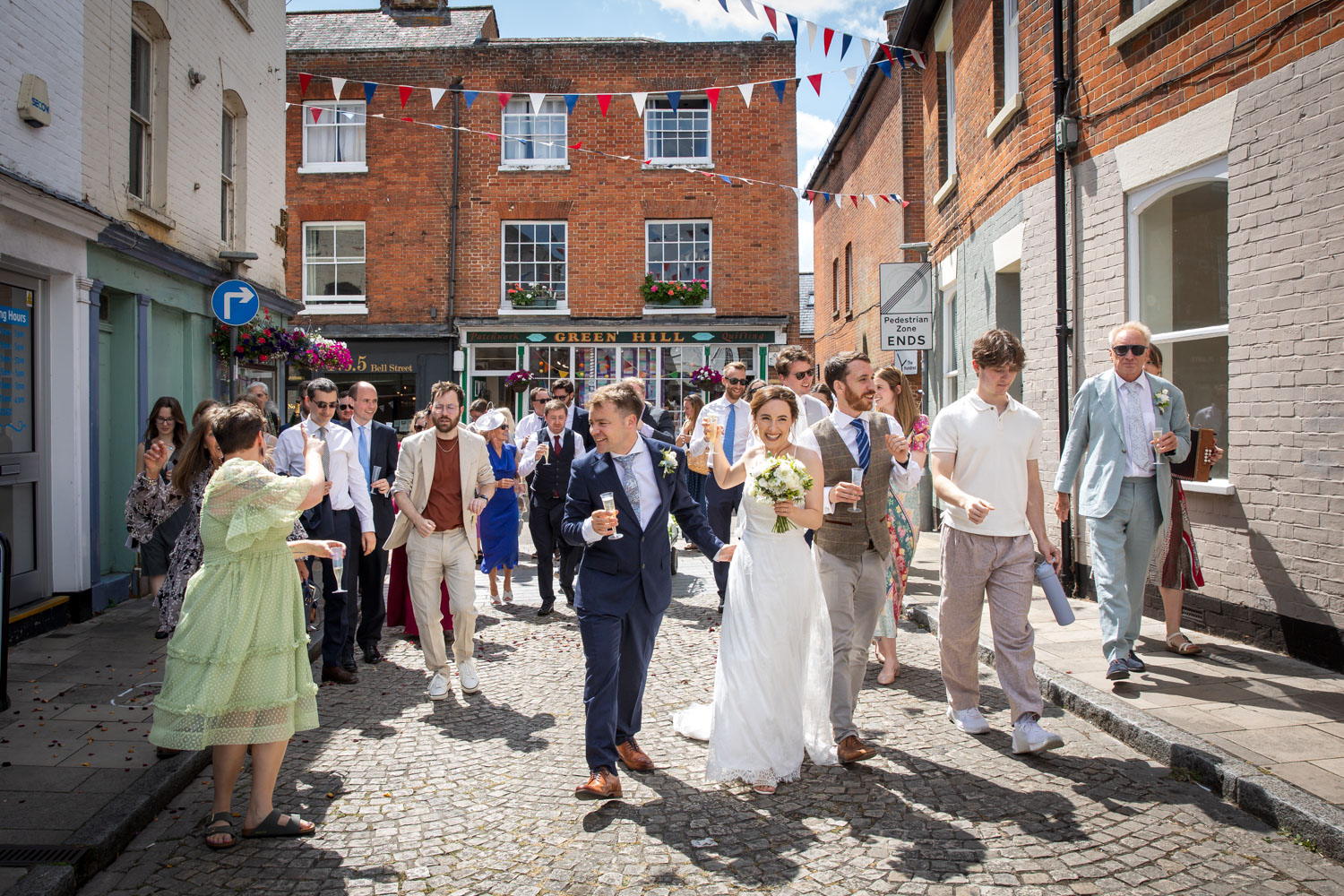 Wedding party walking through charming street by Southampton wedding photographer John Watson