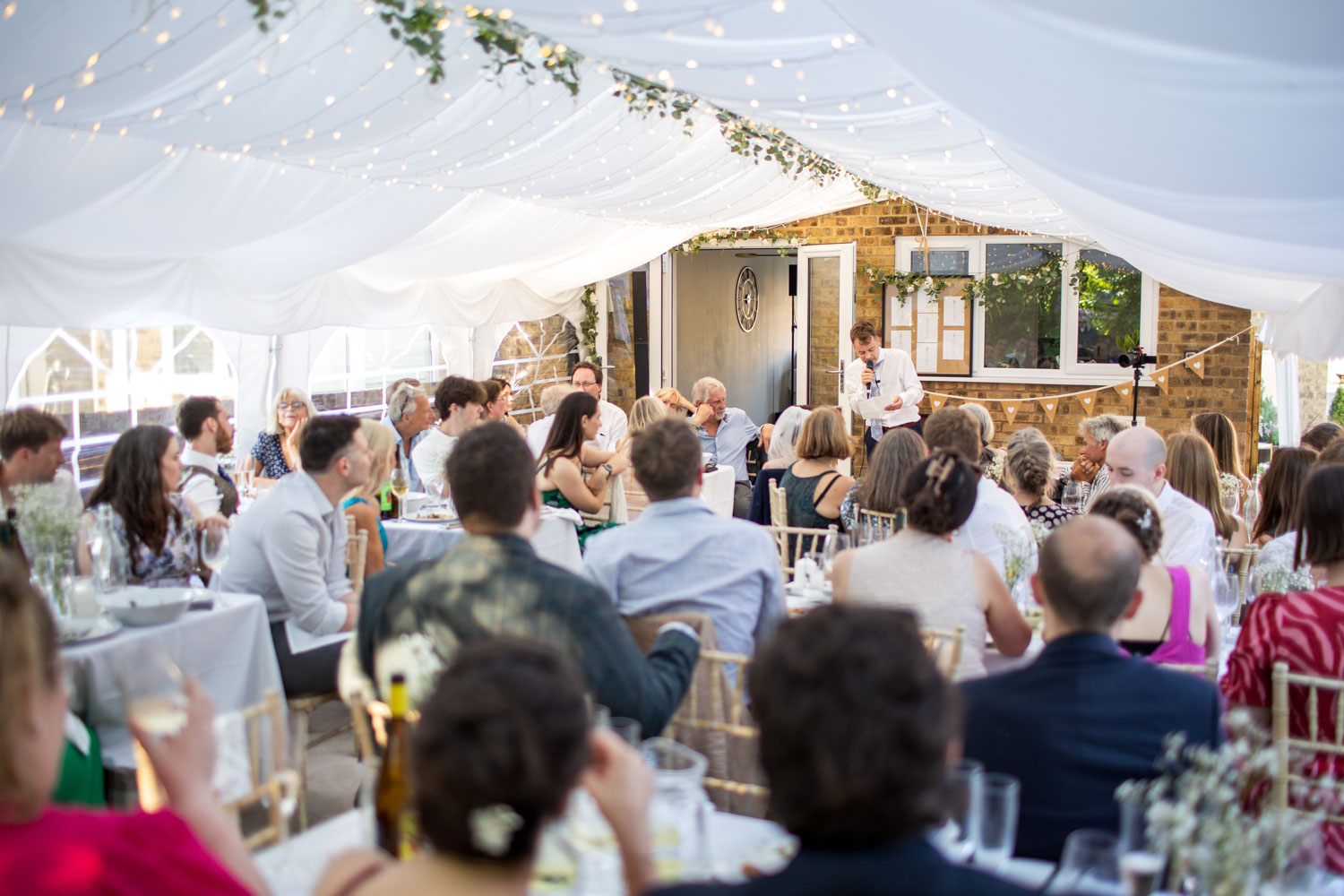 Wedding guests enjoying reception under a marquee by Southampton wedding photographer John Watson