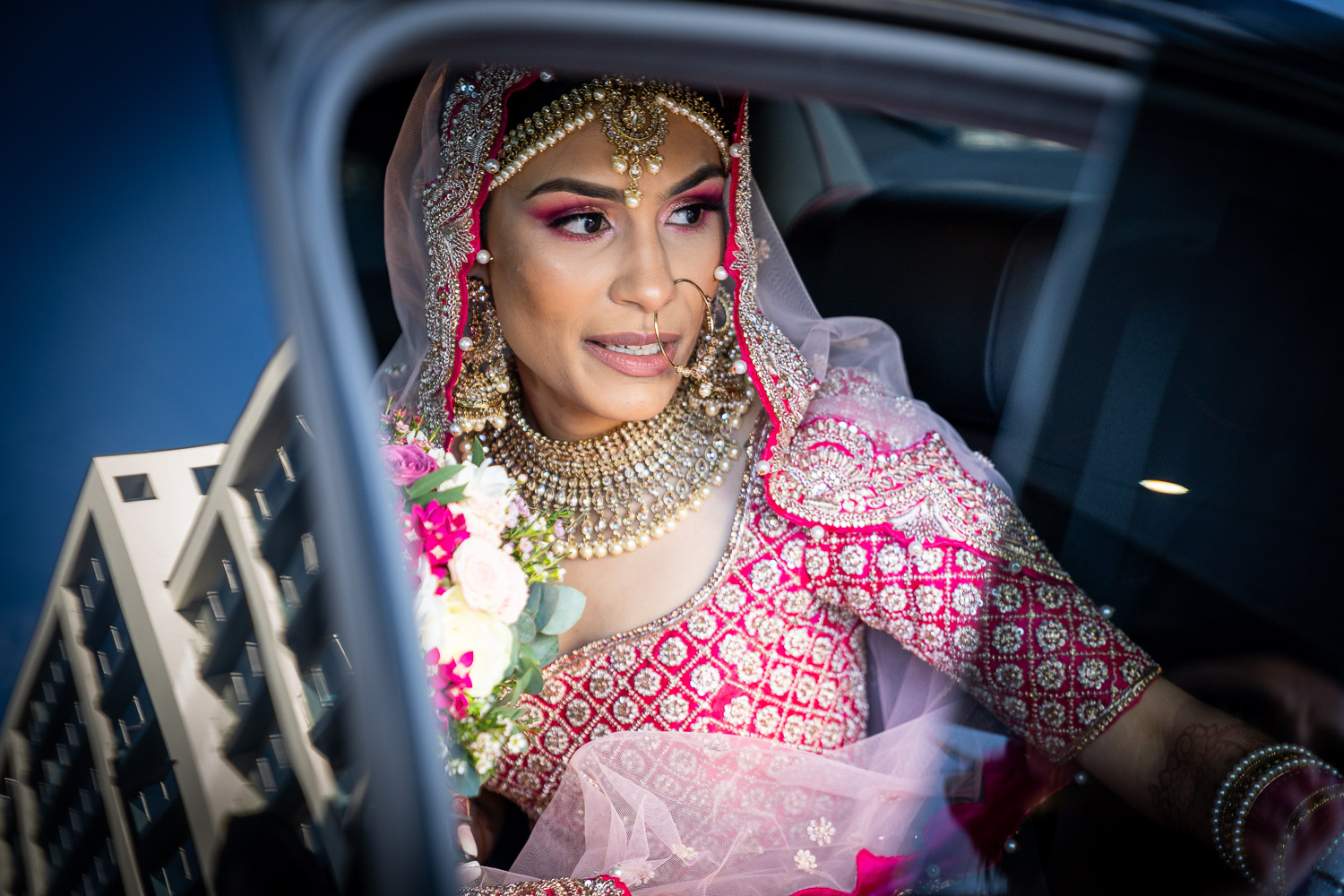 Bride in traditional attire looking out of car by Southampton wedding photographer John Watson