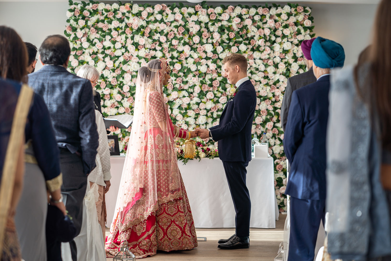 Bride and groom exchanging vows at floral backdrop by Southampton wedding photographer John Watson