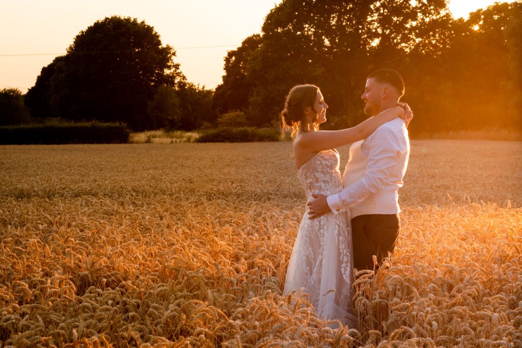 Bride and groom embracing in golden wheat field by Southampton wedding photographer John Watson