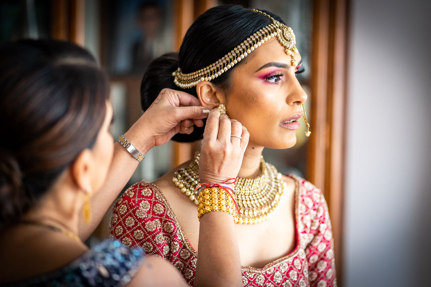 Bride preparing for wedding day adorned in traditional jewellery by Southampton wedding photographer John Watson