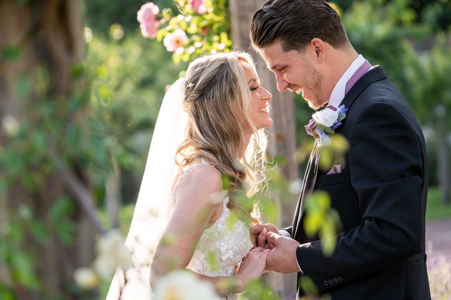 Bride and groom sharing a joyful moment in garden by Southampton wedding photographer John Watson