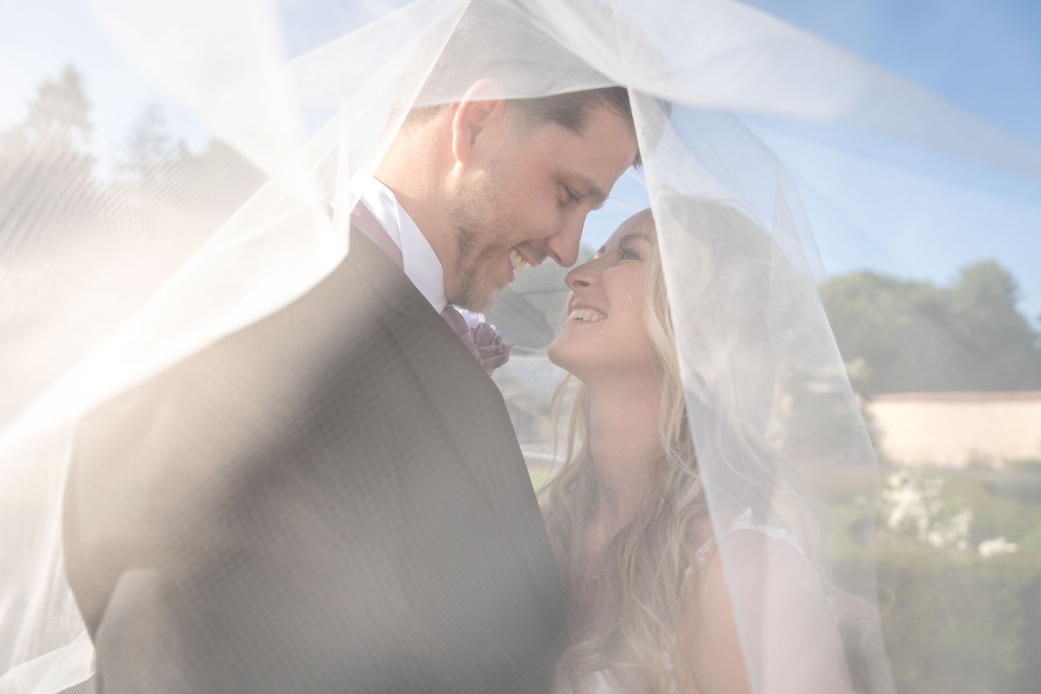 Bride and groom embracing under veil on wedding day by Southampton wedding photographer John Watson