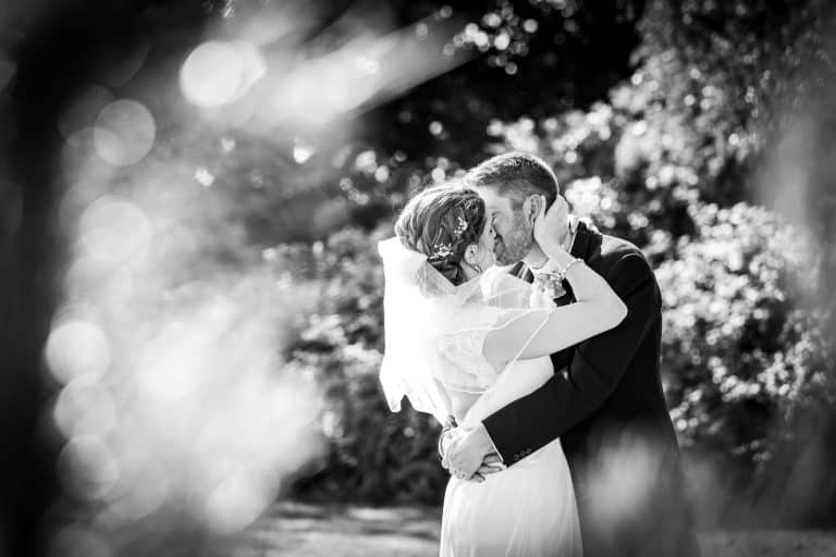 Bride and groom kissing in sunlight by Southampton wedding photographer John Watson