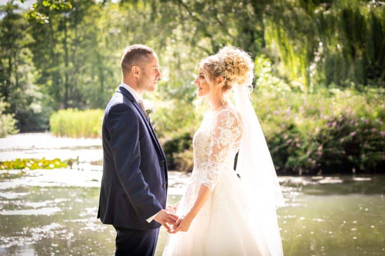 Bride and groom by a serene pond by Southampton wedding photographer John Watson