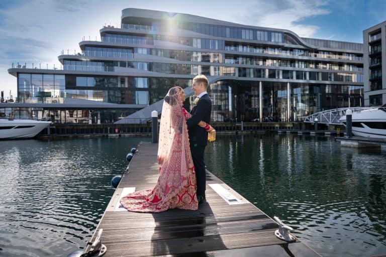 Bride and groom on a pier with modern building backdrop by Southampton wedding photographer John Watson