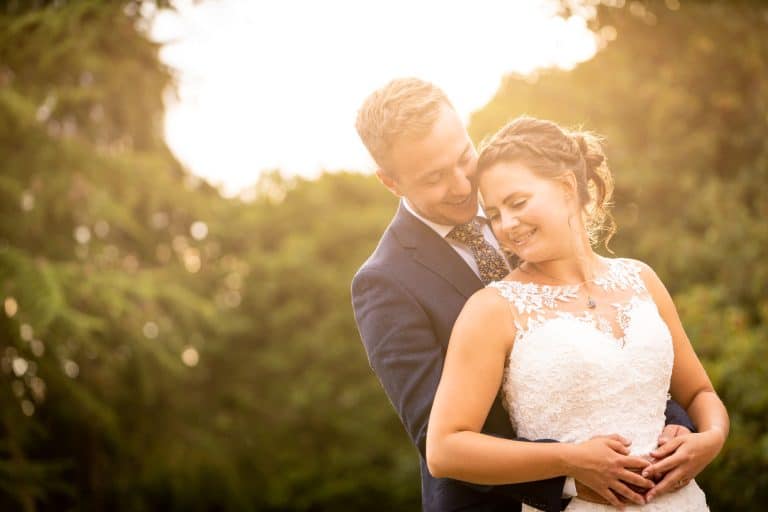 Romantic couple embracing in sunset garden by Southampton wedding photographer John Watson