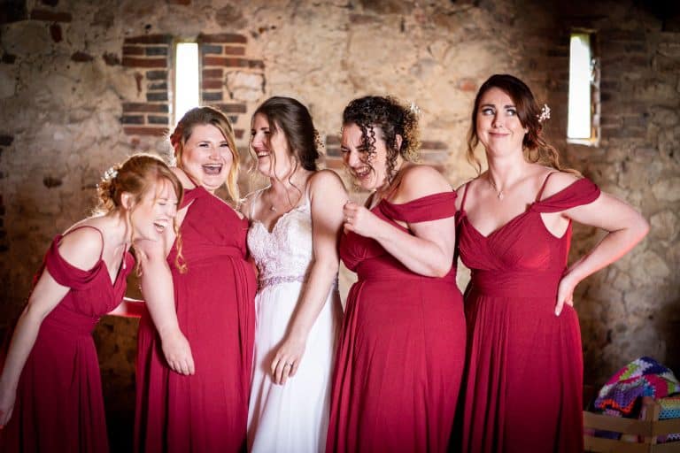 Bridesmaids share a joyful moment in rustic setting by Southampton wedding photographer John Watson