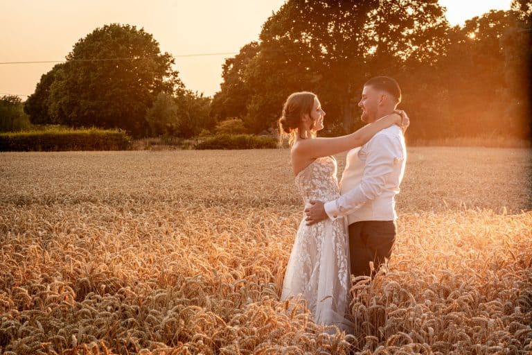 Bride and groom in sunset field embrace by Southampton wedding photographer John Watson