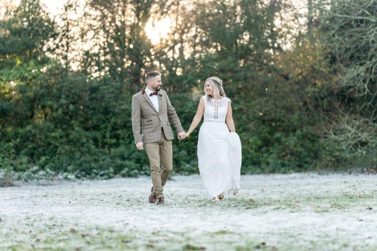 Bride and groom walking on frost covered ground by Southampton wedding photographer John Watson