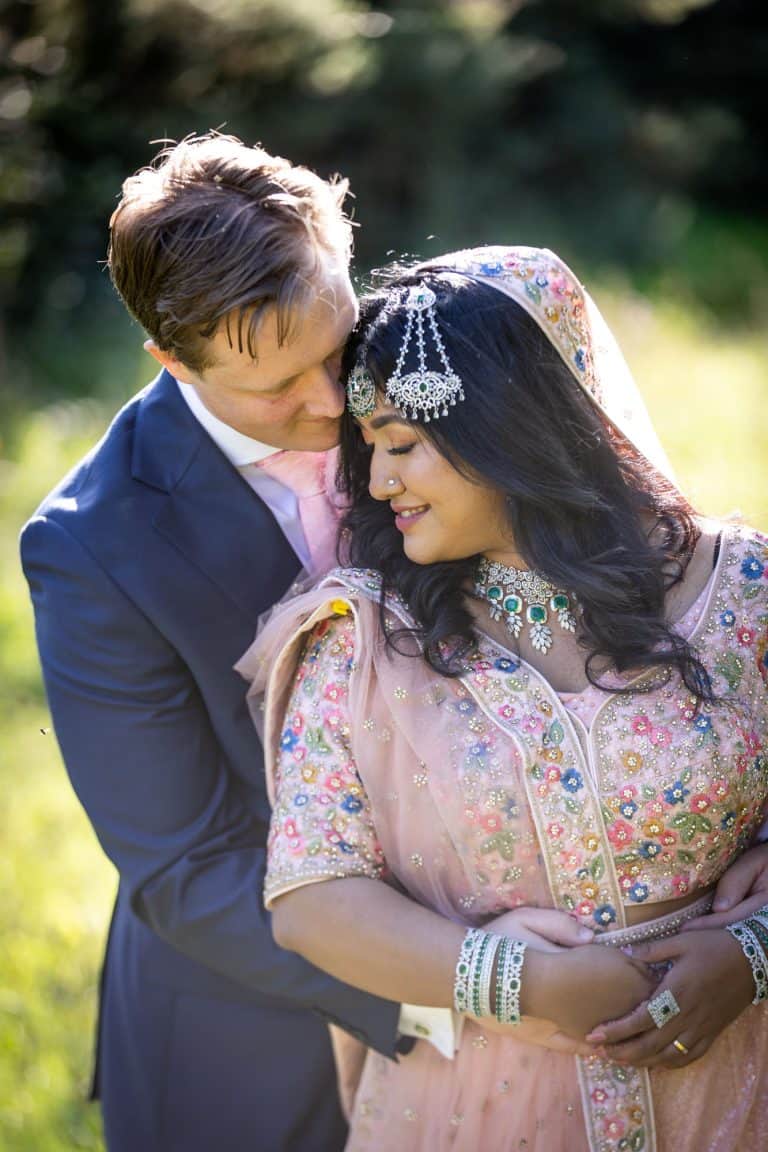 Bride and groom embracing in a sunlit garden setting by Southampton wedding photographer John Watson
