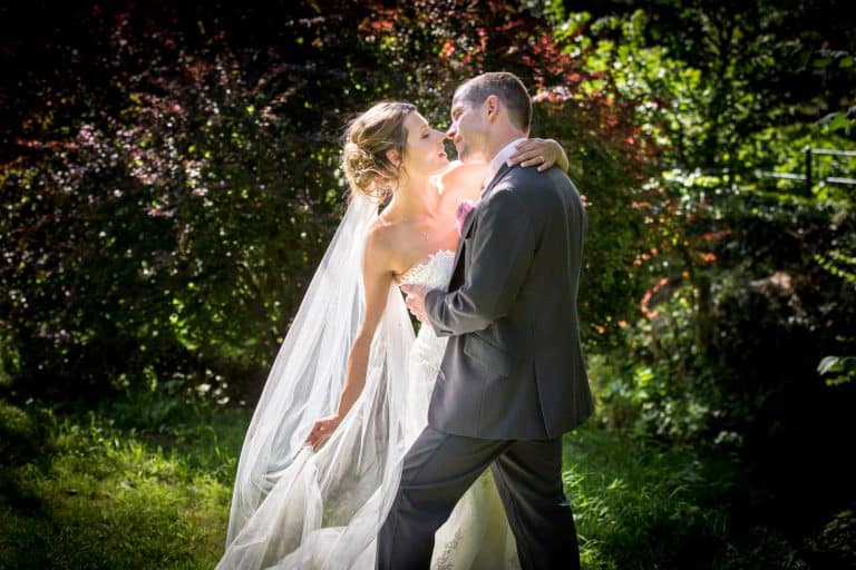 Bride and groom embrace in sunny garden by Southampton wedding photographer John Watson