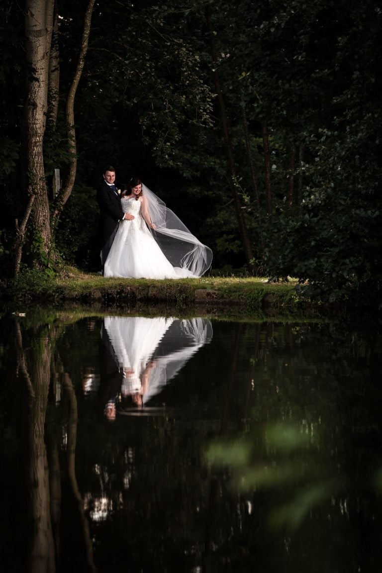 Bride and groom by a serene lake captured by Southampton wedding photographer John Watson