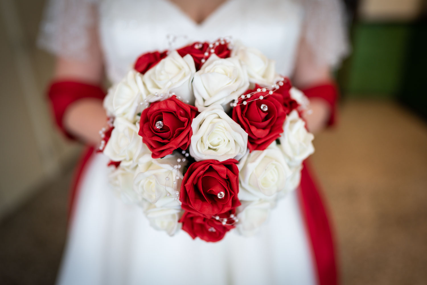 Bride holding red and white rose bouquet by Southampton wedding photographer John Watson