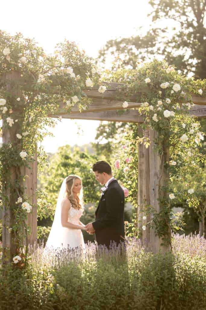Bride and groom in sunny garden archway by Southampton wedding photographer John Watson