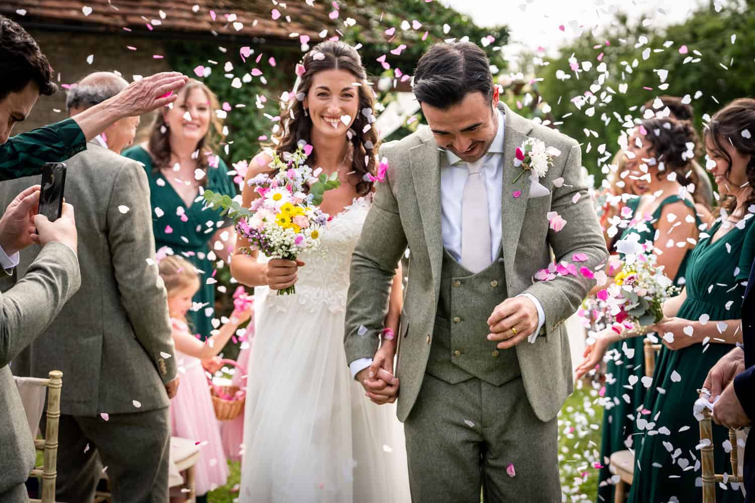 Happy couple walking through confetti shower by Southampton wedding photographer John Watson
