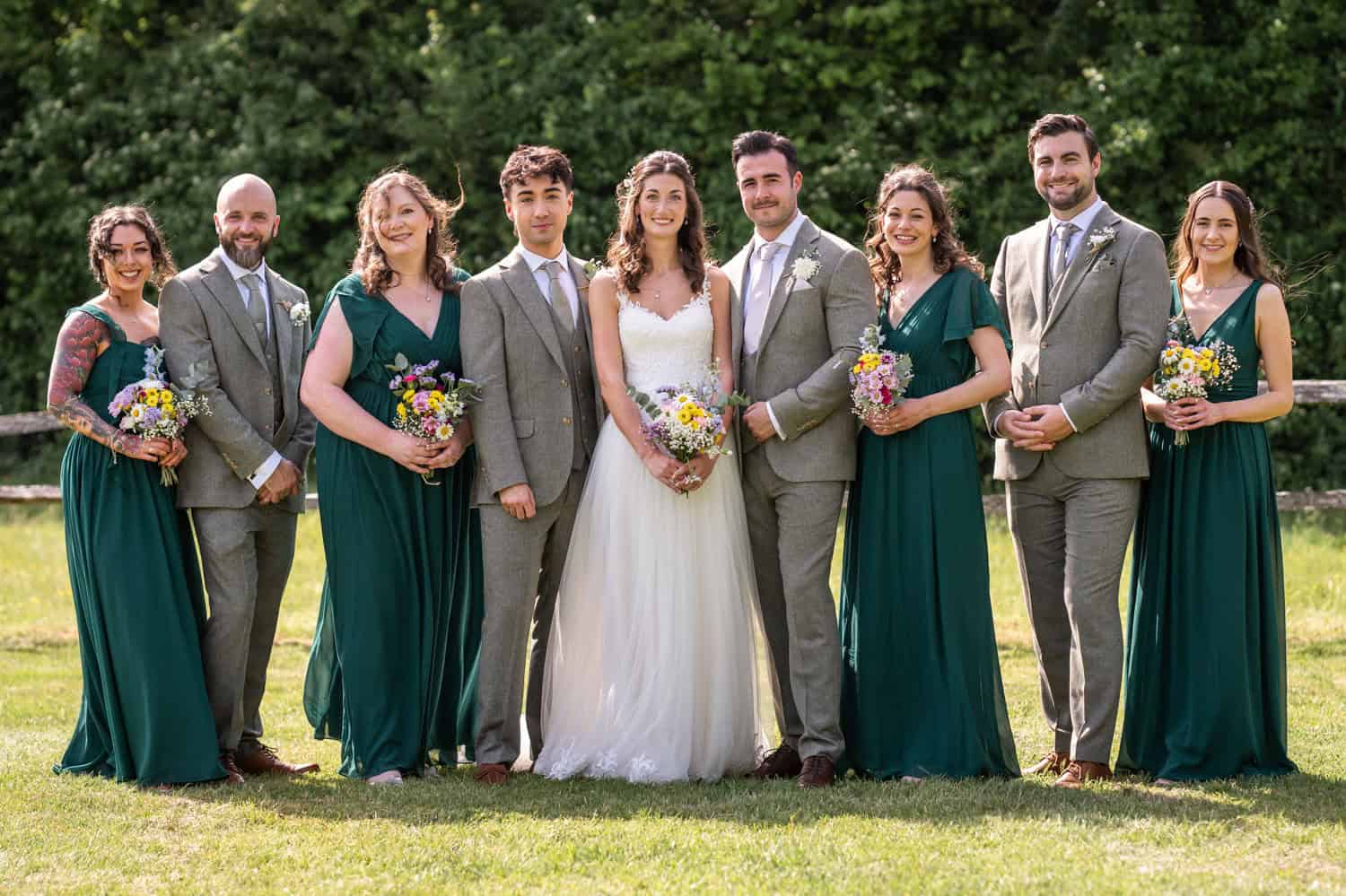 Bridal party posing outdoors in sunlight by Southampton wedding photographer John Watson