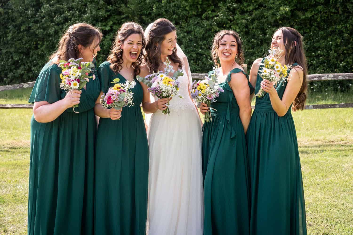 Bridal party in green dresses at outdoor wedding by Southampton wedding photographer John Watson
