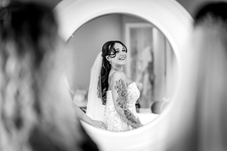 Bride smiling in mirror on wedding day by Southampton wedding photographer John Watson
