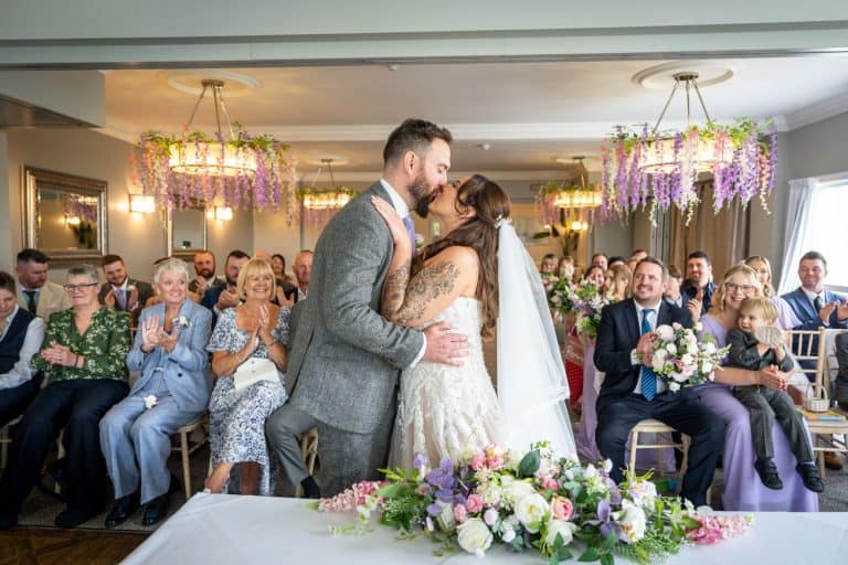Bride and groom kissing at indoor ceremony by Southampton wedding photographer John Watson