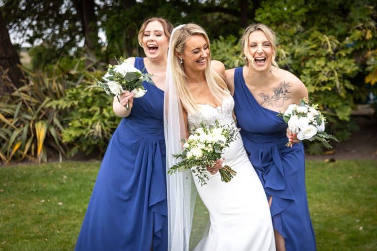 Bride and bridesmaids laughing in garden by Southampton wedding photographer John Watson