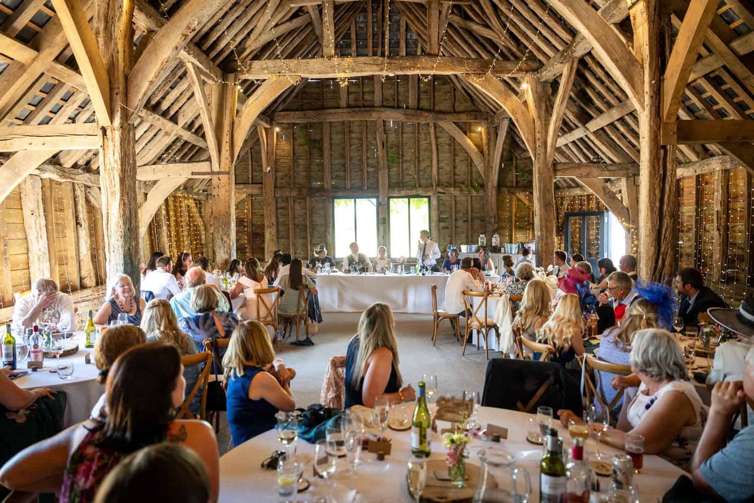 Barn wedding reception with guests seated by Southampton wedding photographer John Watson