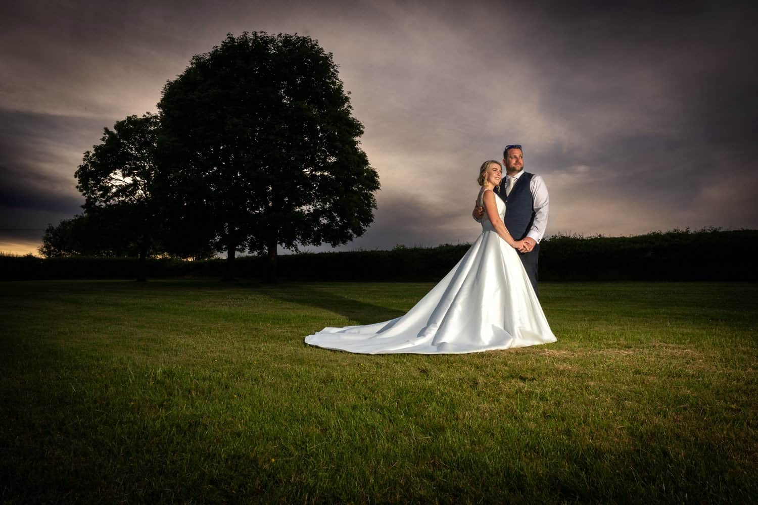 Bride and groom in scenic field by Southampton wedding photographer John Watson