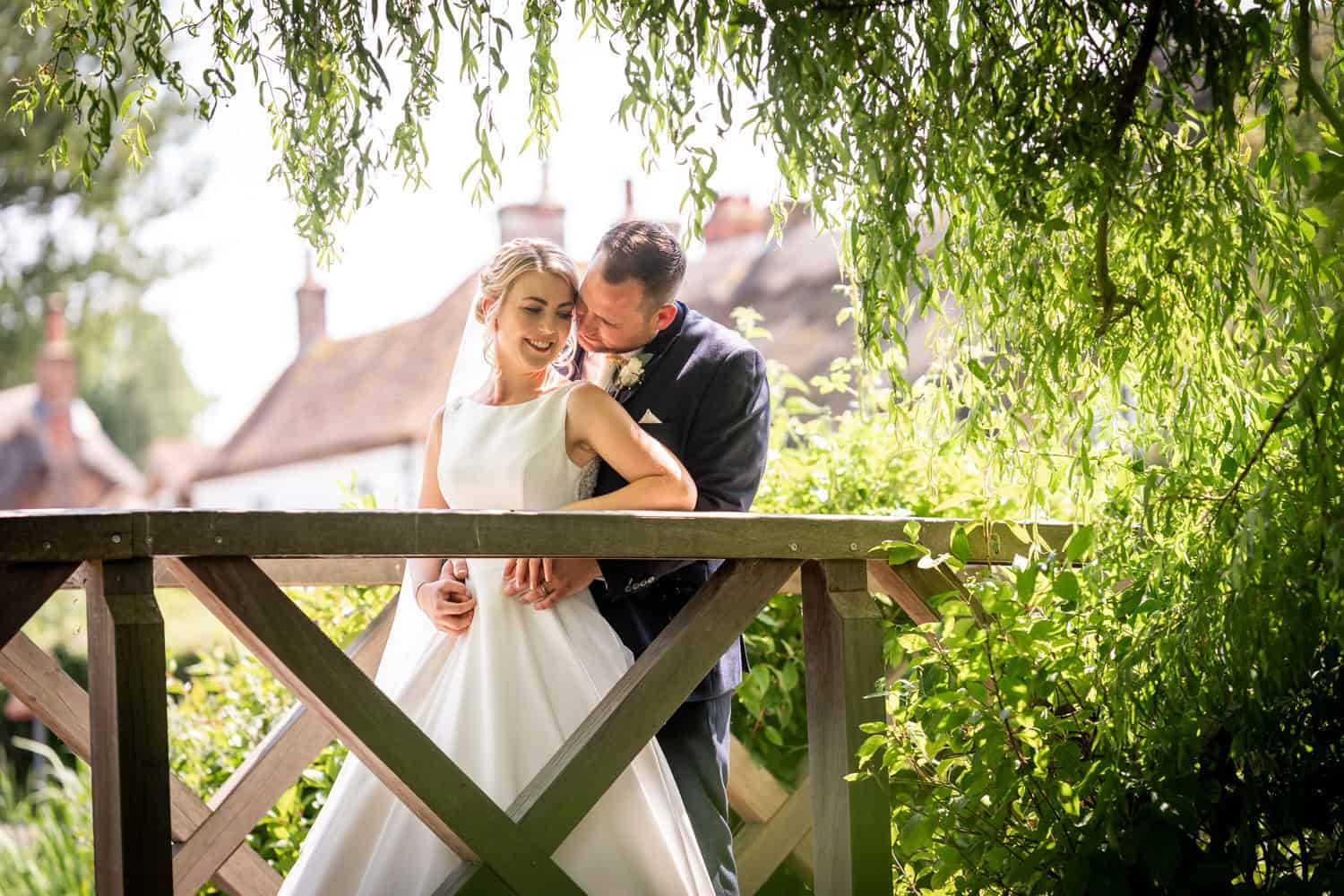 Bride and groom embrace on a wooden bridge by Southampton wedding photographer John Watson