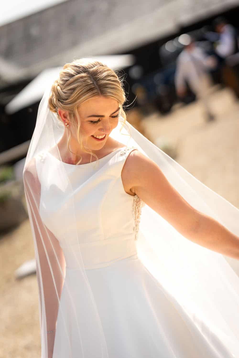 Smiling bride in elegant white gown with veil by Southampton wedding photographer John Watson
